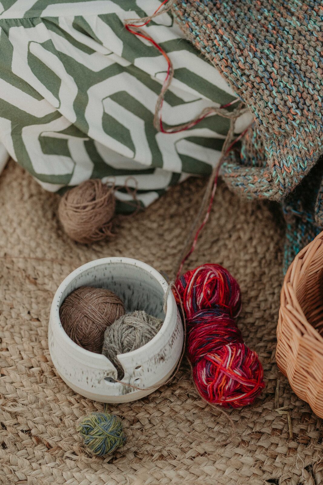 Handmade ceramic yarn bowl with a spiral yarn guide, styled with knitting wool