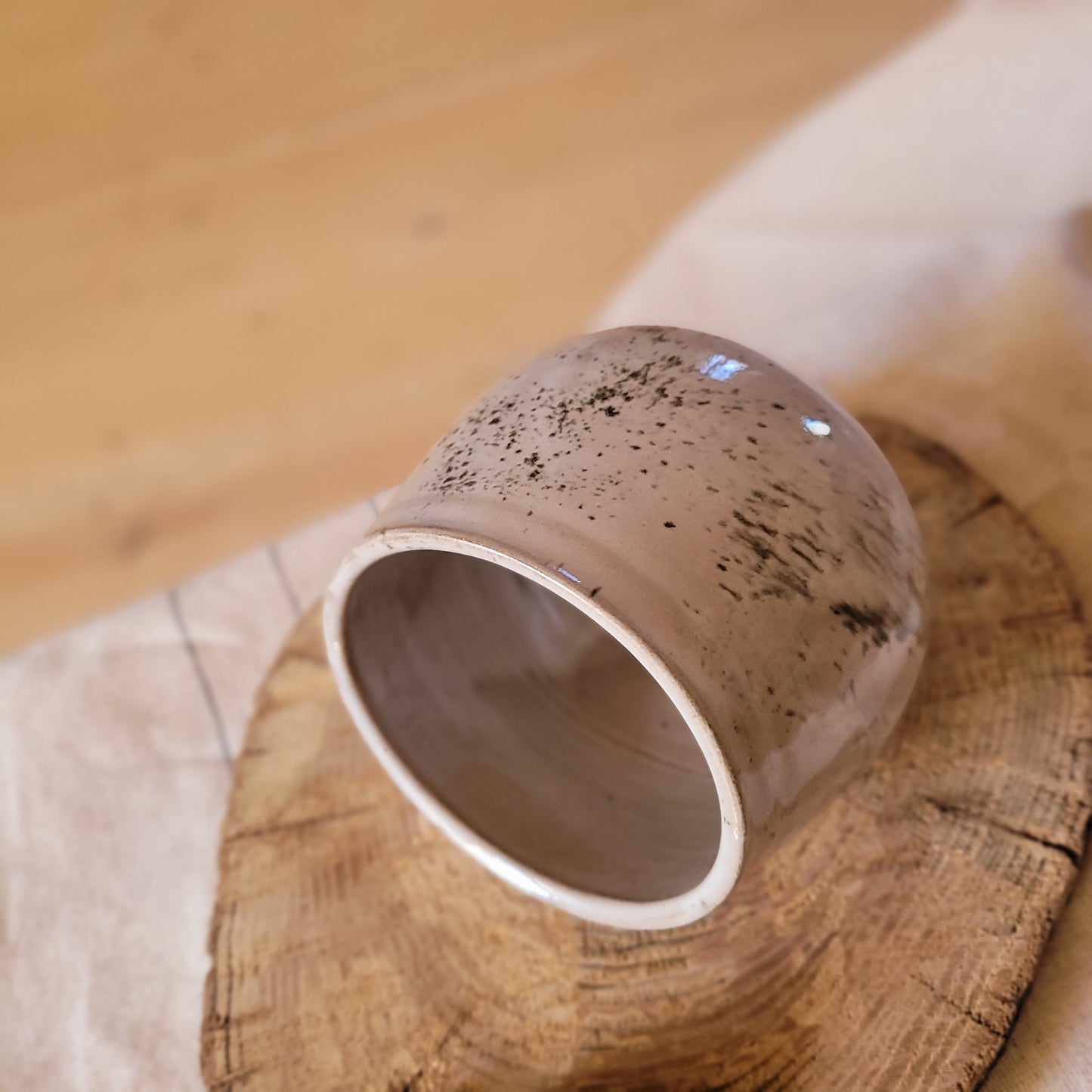 Grauer handgemachter Keramik-Salztopf mit gesprenkelter Glasur und Holzlöffel.