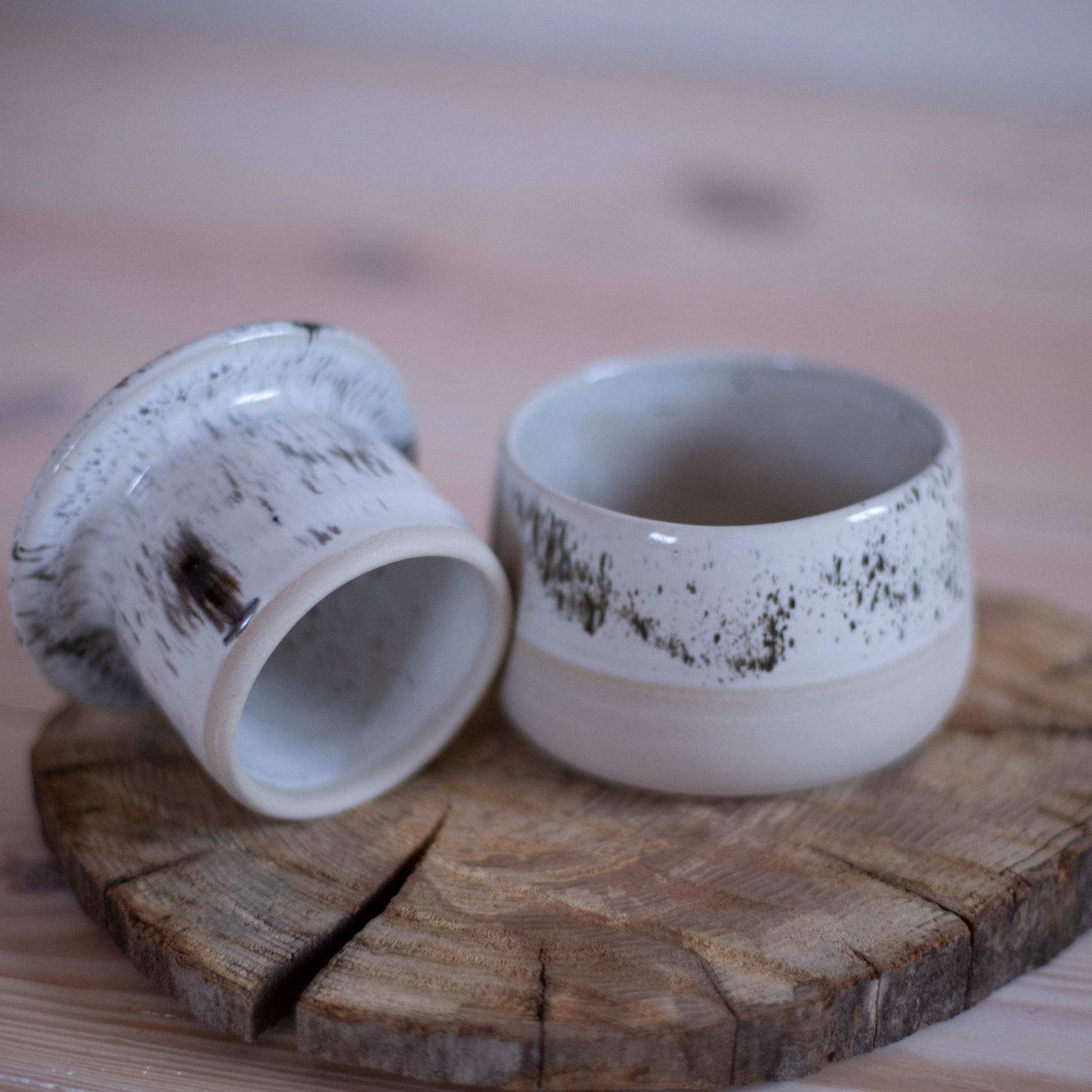 French butter dish with a white speckled glaze, sitting on a rustic wooden cutting board.