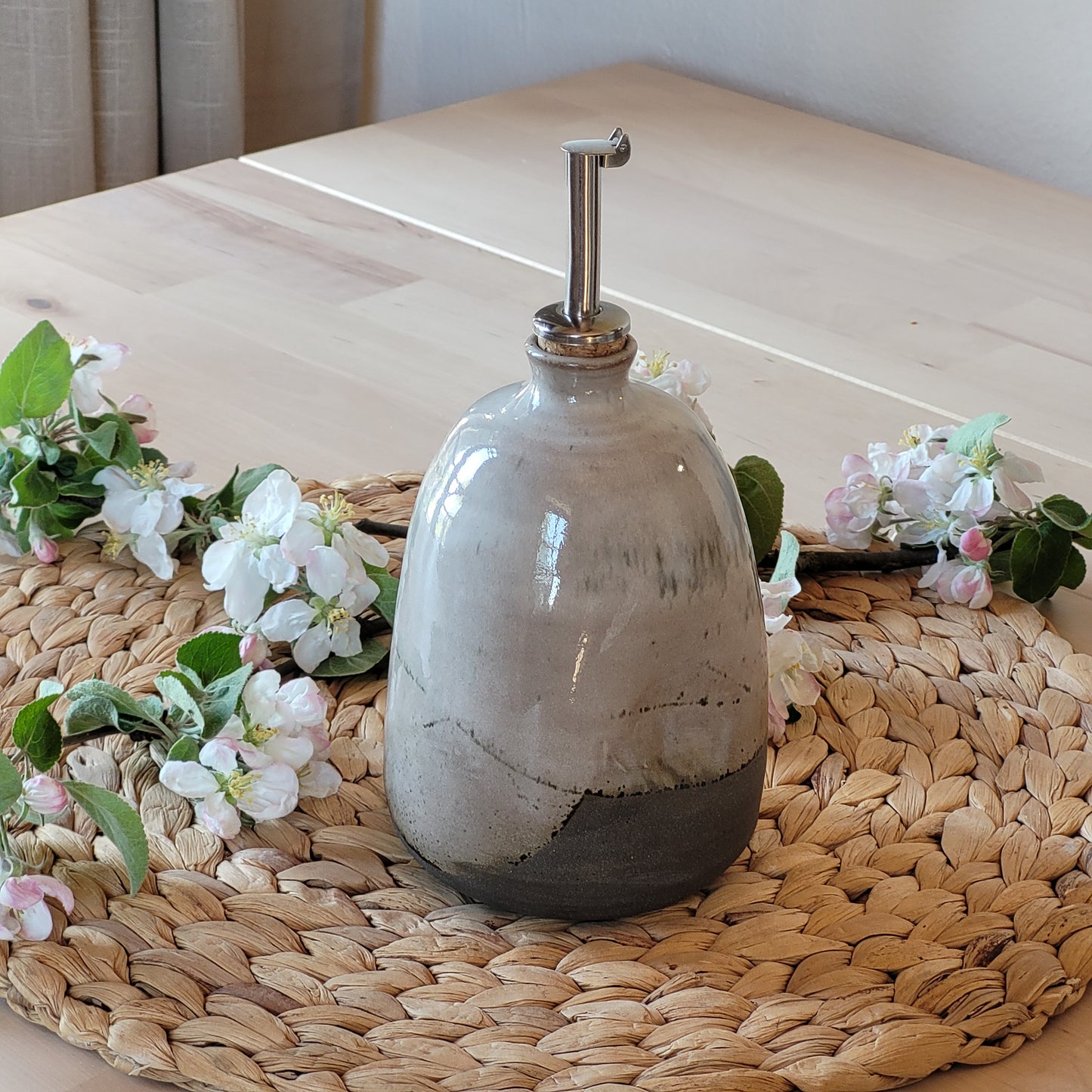 This handmade stoneware oil bottle is perfect for adding character to your kitchen. With a speckled white glaze and raw clay interior, each piece is one-of-a-kind.