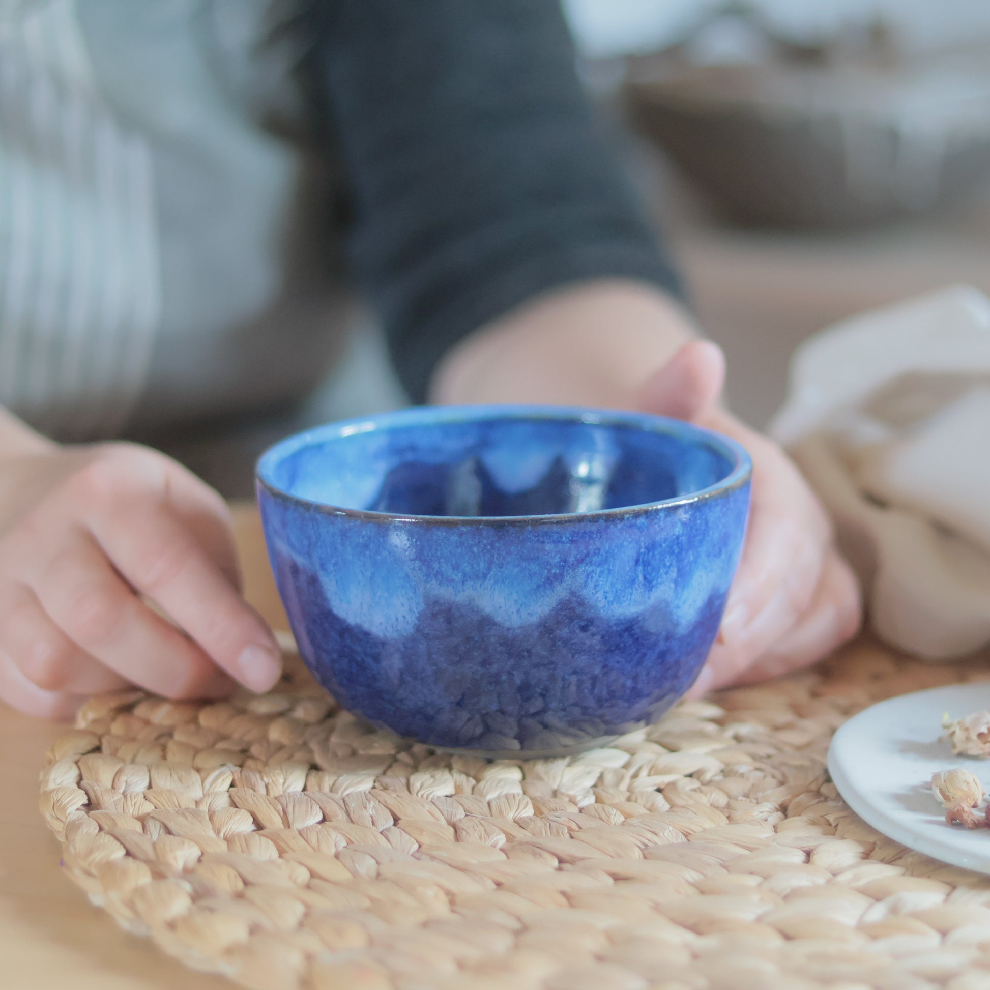 Bol à matcha en grès fait main, glaçure bleue ombrée, tenu dans les mains
