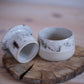 French butter dish with a white speckled glaze, sitting on a rustic wooden cutting board.