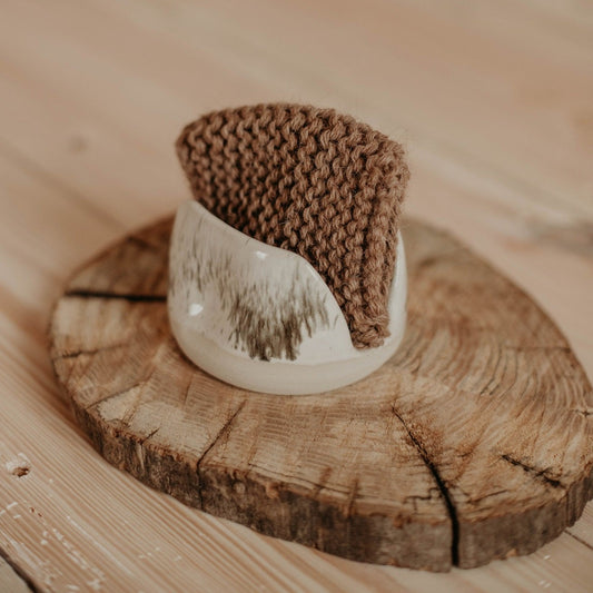 A handcrafted ceramic sponge holder made from white stoneware with black speckles.